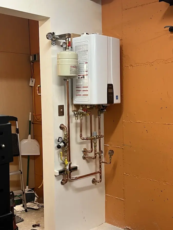 Plumbing technician inspecting water heater connections in Rolesville